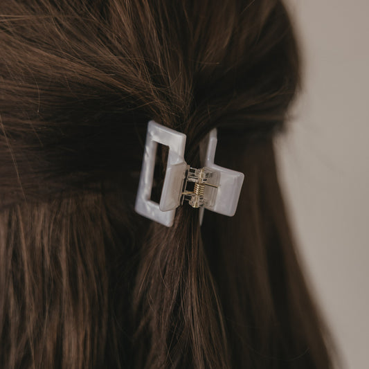 Kleine eckige Haarspange in Perlmutt-Optik im braunen Haar von hinten getragen