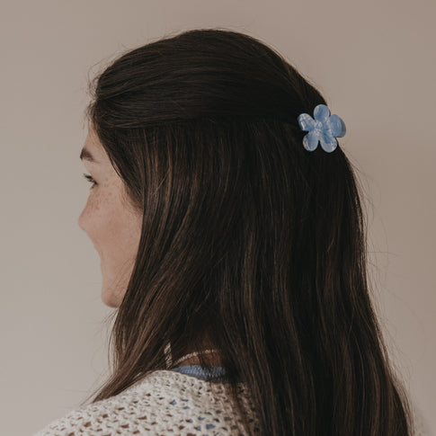 Seitliche Ansicht Haarspange Blume hellblau im halboffenen Haar getragen