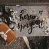 Graue Fußmatte mit schwarzem Schriftzug „Hereinspaziert“ in einer festlichen Geburtstagsszene mit Discokugeln, Konfetti, Wunderkerzen, Getränken und einem verpackten Geschenk.