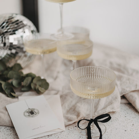 Dekorative Szene mit mehreren Champagnergläsern, Eukalyptus und Disco-Kugel.