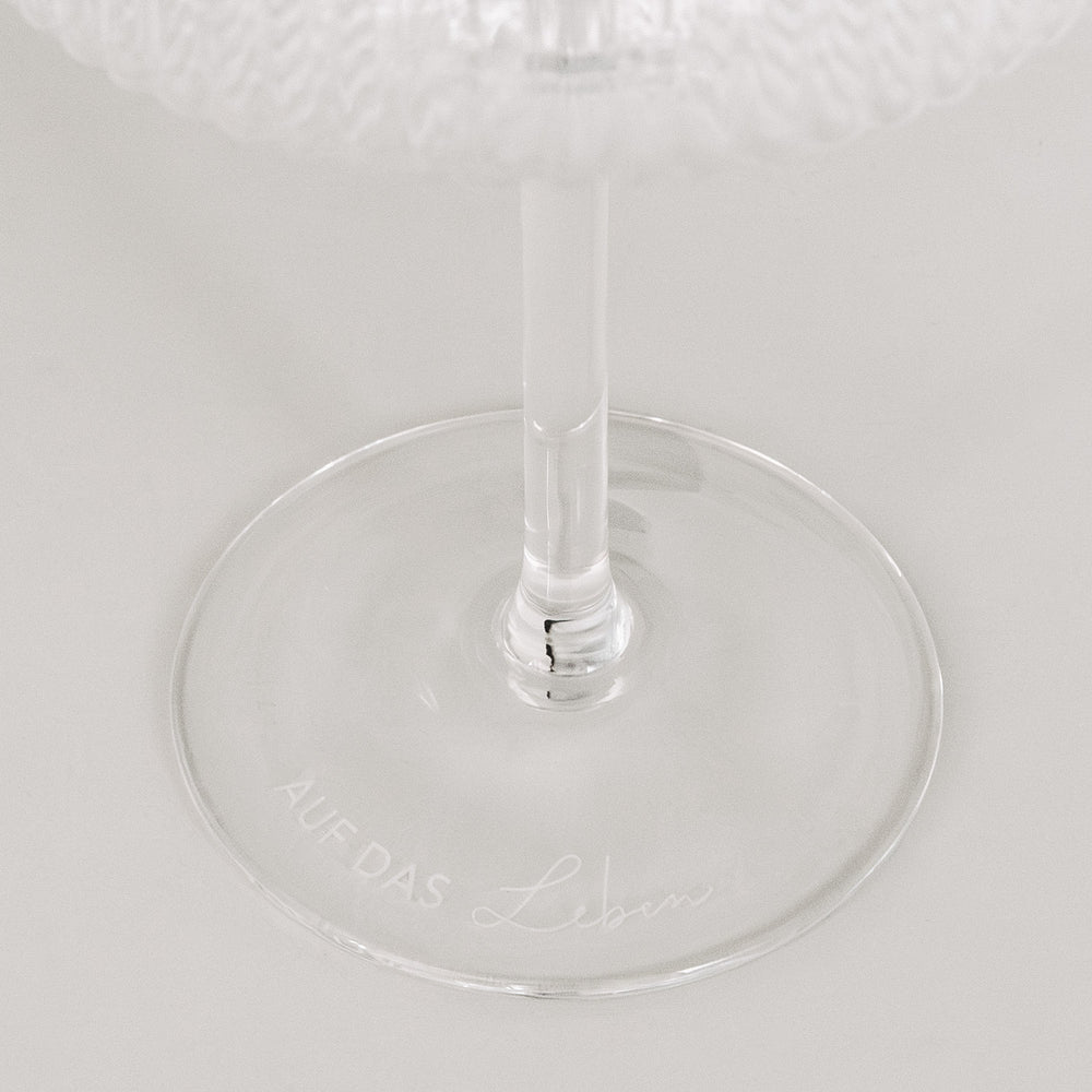 Detailaufnahme der Gravur „Auf das Leben“ auf Glasboden, minimalistisch auf Weiß.