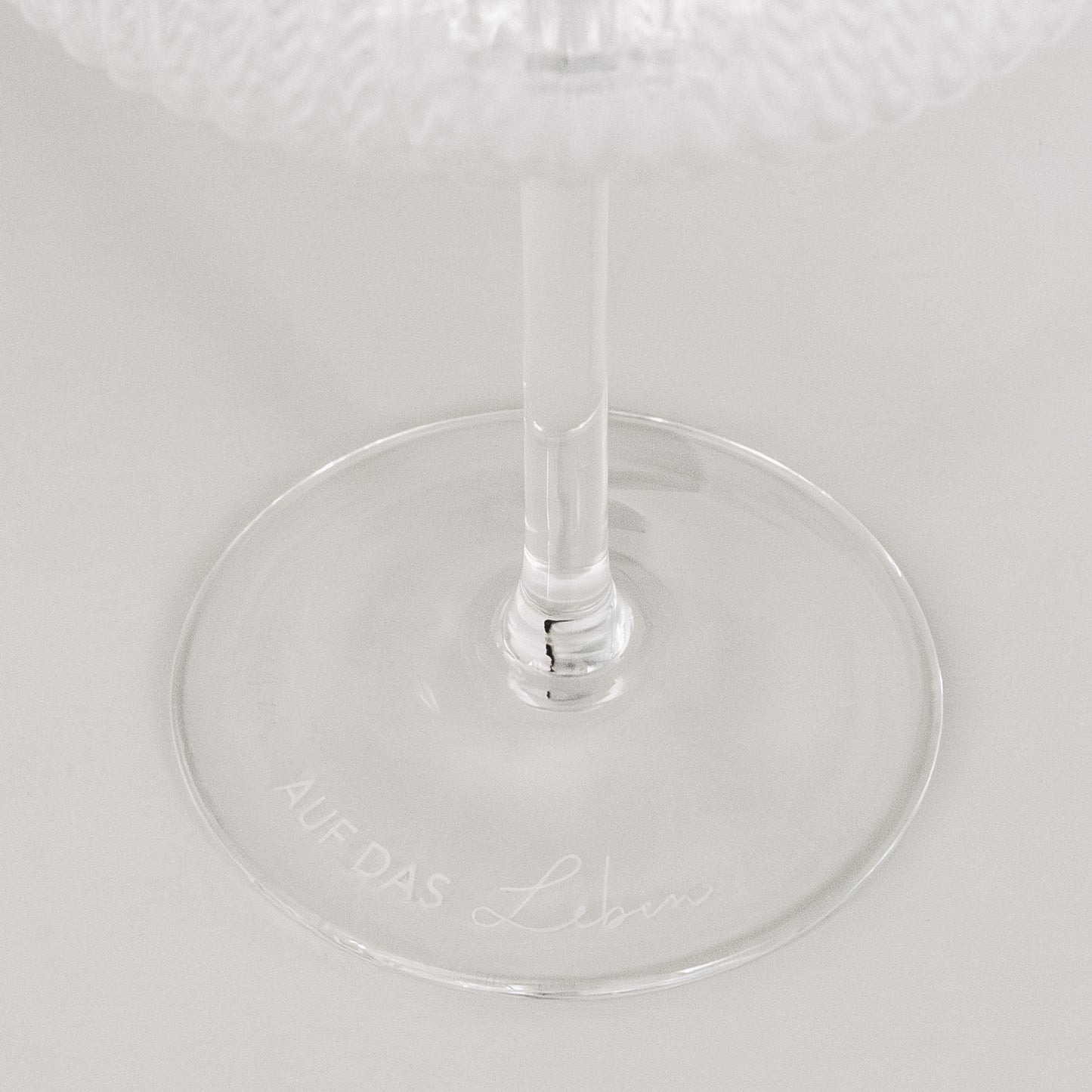 Detailaufnahme der Gravur „Auf das Leben“ auf Glasboden, minimalistisch auf Weiß.