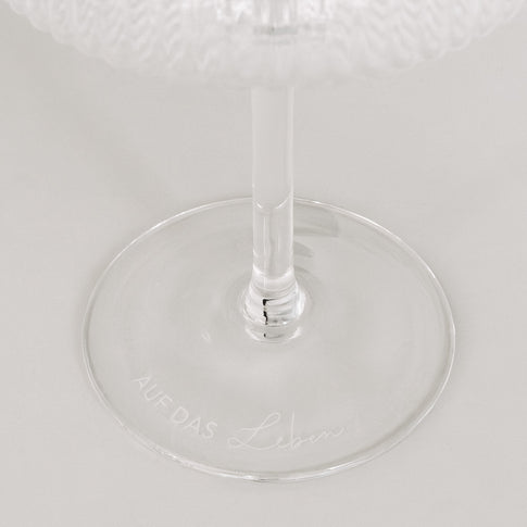 Detailaufnahme der Gravur „Auf das Leben“ auf Glasboden, minimalistisch auf Weiß.