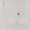 Nahaufnahme des Trinkglases mit schwebender 3D-Geistfigur aus Glas auf hellem Hintergrund
