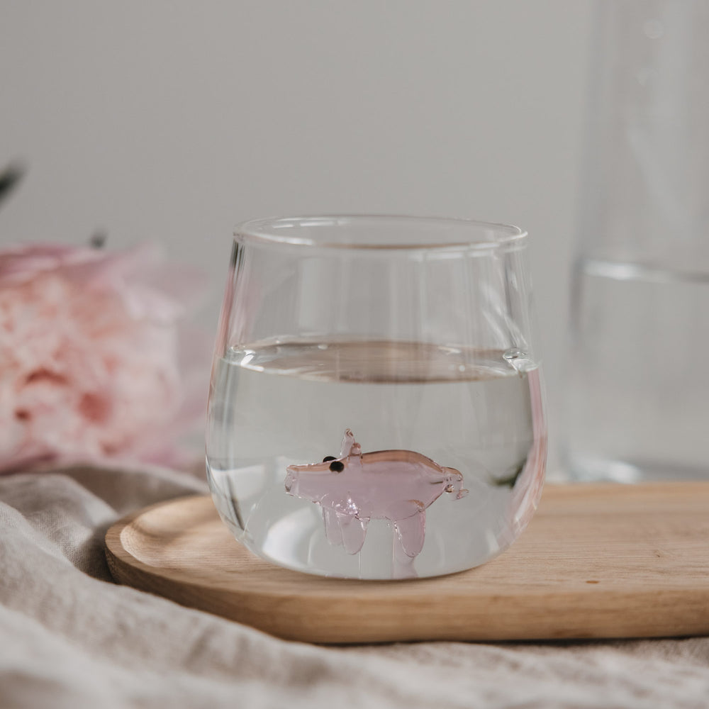 Trinkglas mit Schwein Motiv gefüllt mit Wasser auf Holzbrett, stilvolles Glas