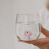 Trinkglas mit rosa Schwein im Boden, in der Hand gehalten, klares Glasdesign