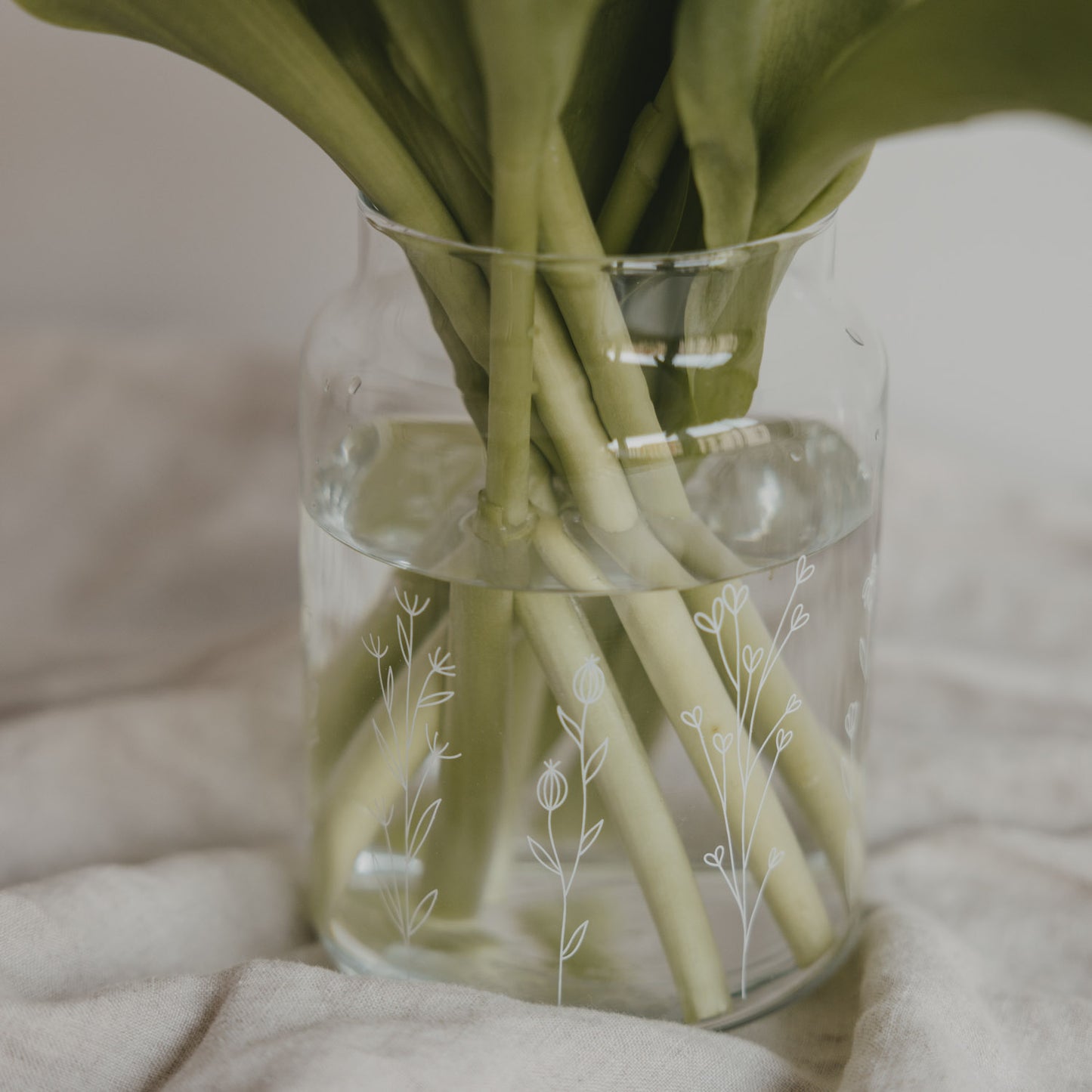 Glasvase mit Wasser und Tulpenstielen, feines Blumenwiesen-Motiv, Nahaufnahme