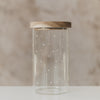 Vorratsglas mit weißen Herzen und rundem Holzdeckel vor beigem Hintergrund