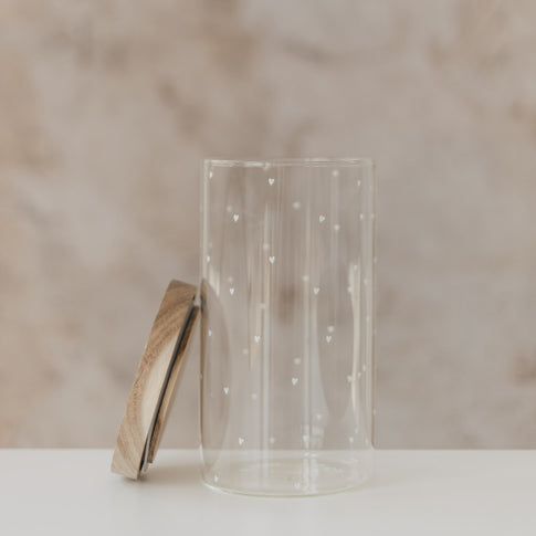 Offenes Vorratsglas mit weißen Herzen und seitlich angelehntem Holzdeckel