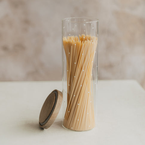Offenes Vorratsglas mit kleinen weißen Herzen und Spaghetti, der Holzdeckel lehnt seitlich am Glas.