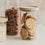 Vorratsglas mit schwarzen Herzchen und Holzdeckel, gefüllt mit Keksen, neben Gläsern mit Müsli und Haferflocken.