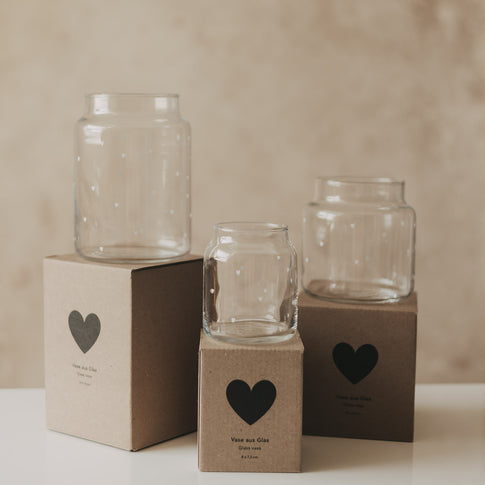 Drei Glasvasen mit Herzprint in verschiedenen Größen auf Geschenkboxen arrangiert