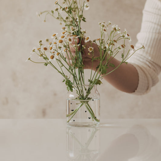 Glasvase mit schwarzen Herzen, mit locker arrangierten Blumen