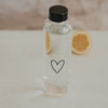 Trinkflasche Herz 750 ml aus Glas mit Zitrone im Hintergrund, stilvoll und schlicht