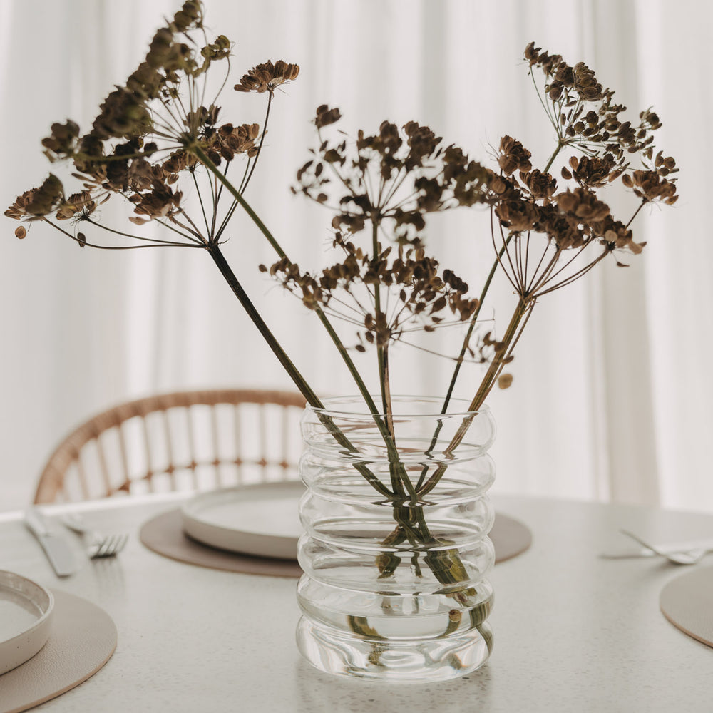 Bubble Vase aus transparentem Glas mit getrockneten Doldenblüten als Tischdekoration.
