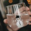 Detailaufnahme des transparenten Trinkglases mit weißer Schneemannfigur und schwarzem Hut im Glasboden.