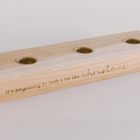 Nahaufnahme Holzkerzenbrett mit Kerzenplätzen und Gravur Christmas