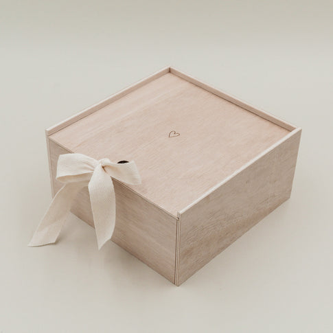 Erinnerungsbox Herz aus Holz mit Schleifenband geschlossen, minimalistisch vor hellem Hintergrund.