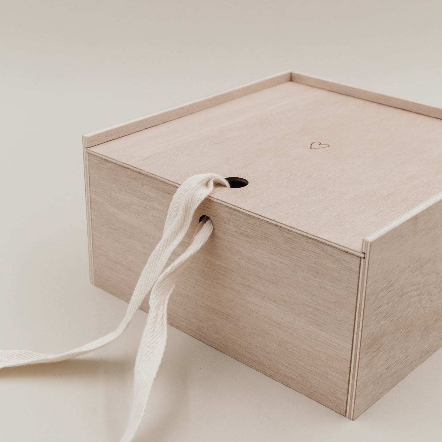 Nahaufnahme des geschlossenen Deckels der Erinnerungsbox Herz, durchzogen von einem Stoffband.