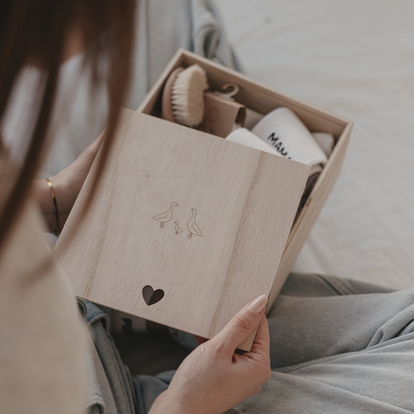 Holz Erinnerungsbox mit Gänsemotiv und Herzdetail, gefüllt mit Babygeschenk, stilvolle Aufbewahrung für Erinnerungen