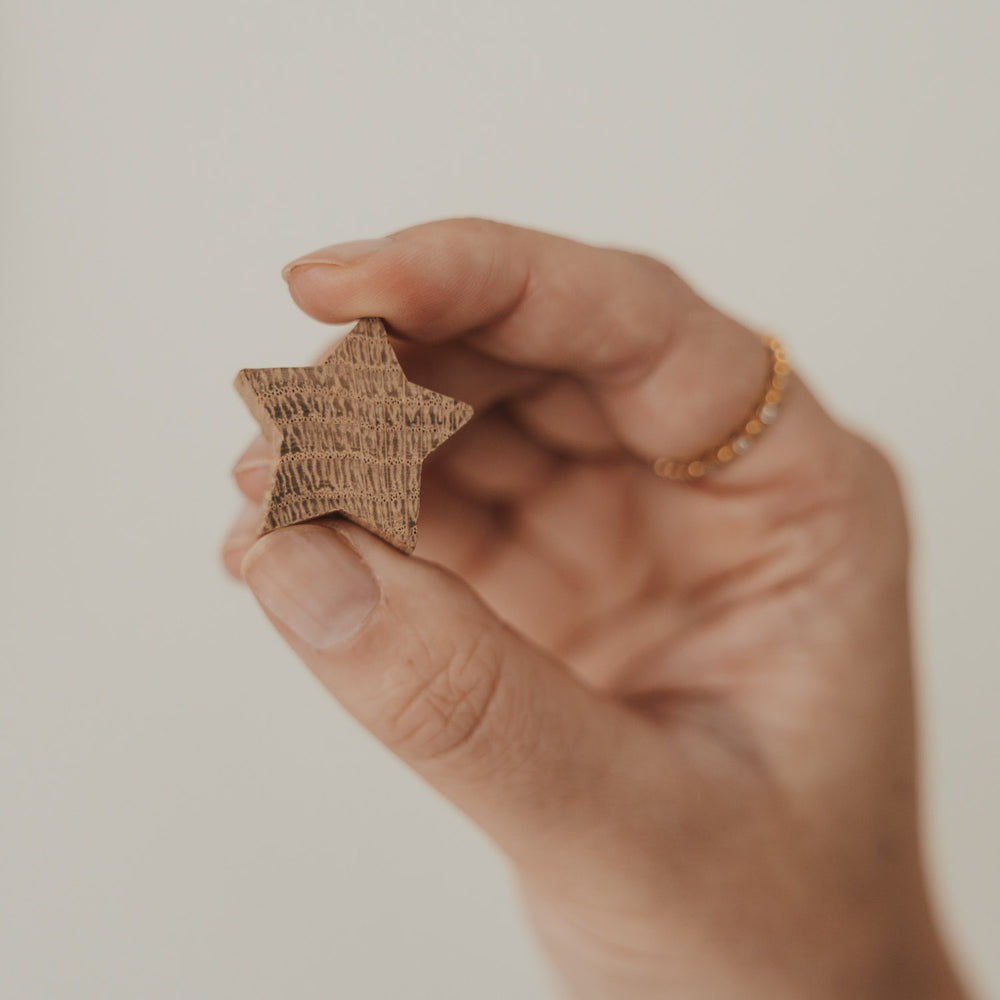 Sternförmiger Holzmagnet mit natürlicher Maserung in der Hand gehalten