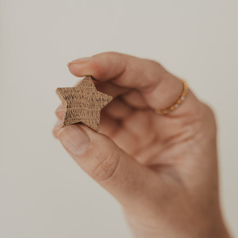 Sternförmiger Holzmagnet mit natürlicher Maserung in der Hand gehalten