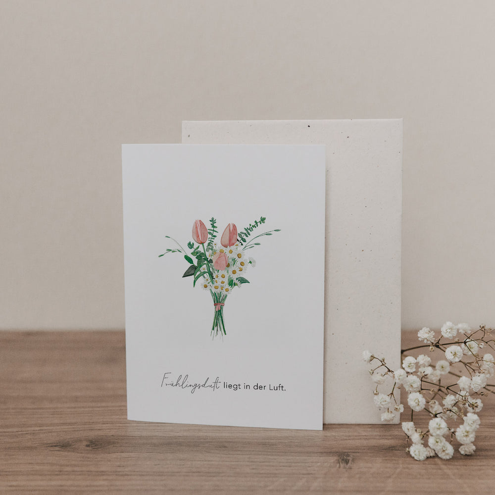 Klappkarte mit gemaltem Frühlingsblumenstrauß und dem Text „Frühlingsduft liegt in der Luft“, mit passendem Umschlag.