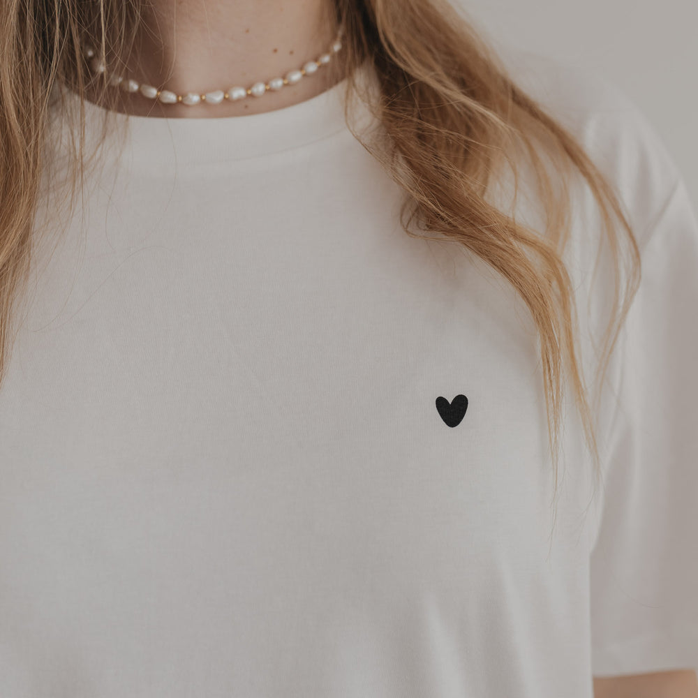 Detailansicht: Schwarzes Herz auf weißem T-Shirt mit Perlenkette