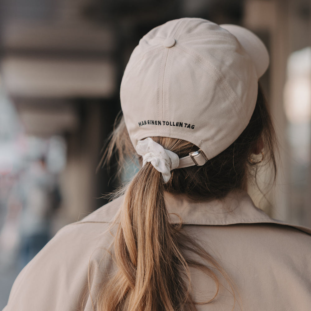 Rückseite beige Cap mit Schriftzug „Hab einen tollen Tag“ und verstellbarem Verschluss