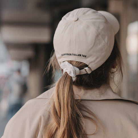 Rückseite beige Cap mit Schriftzug „Hab einen tollen Tag“ und verstellbarem Verschluss