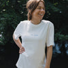 Frau im weißen „Ocean Child“ T-Shirt mit Frontprint, natürlicher Outdoor Look