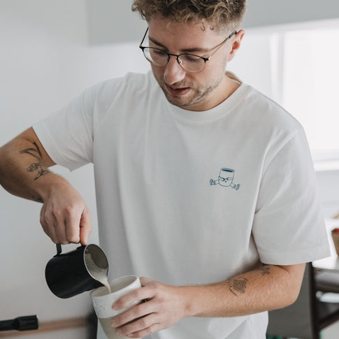 Mann bereitet Kaffee im weißen T-Shirt mit kleiner Kaffee Illustration, Detail Frontprint