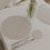 Warmes Tischarrangement mit cremefarbenem Platzset und Blumenvase mit Tulpen.