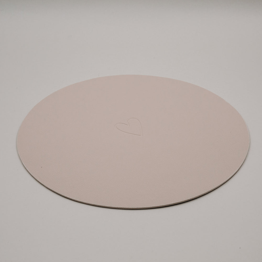 Rundes cremefarbenes Platzset von Eulenschnitt mit zart eingeprägtem Herzmotiv auf hellem Hintergrund.