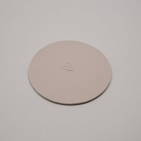 Wendbarer Untersetzer in Creme mit Herzprägung, runde Form und feine Lederstruktur.