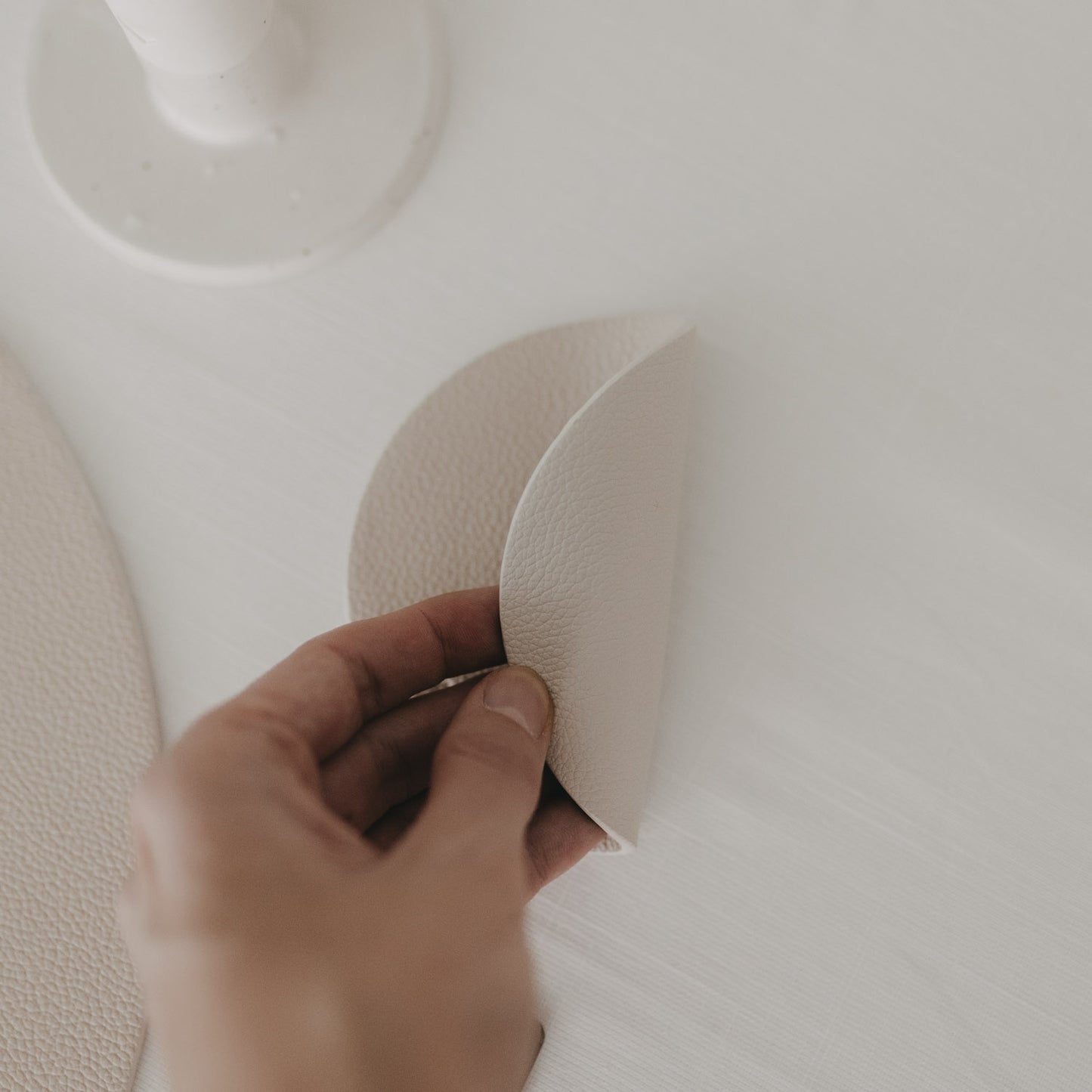 Flexibler Untersetzer in Creme wird gebogen, Struktur und Material deutlich sichtbar.