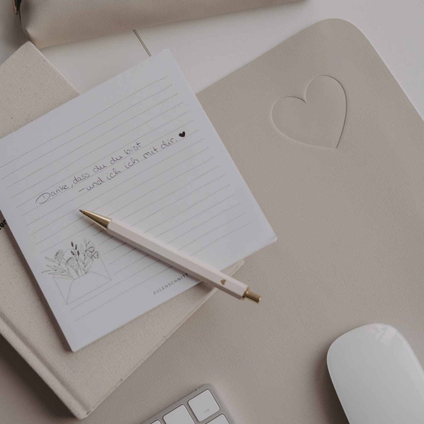 Taupe Schreibtischunterlage mit Herz-Prägung, Notizblock und Stift auf hellem Schreibtisch