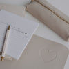 Detail Notizblock auf taupe Schreibtischunterlage mit Herz, Stift und Federmäppchen