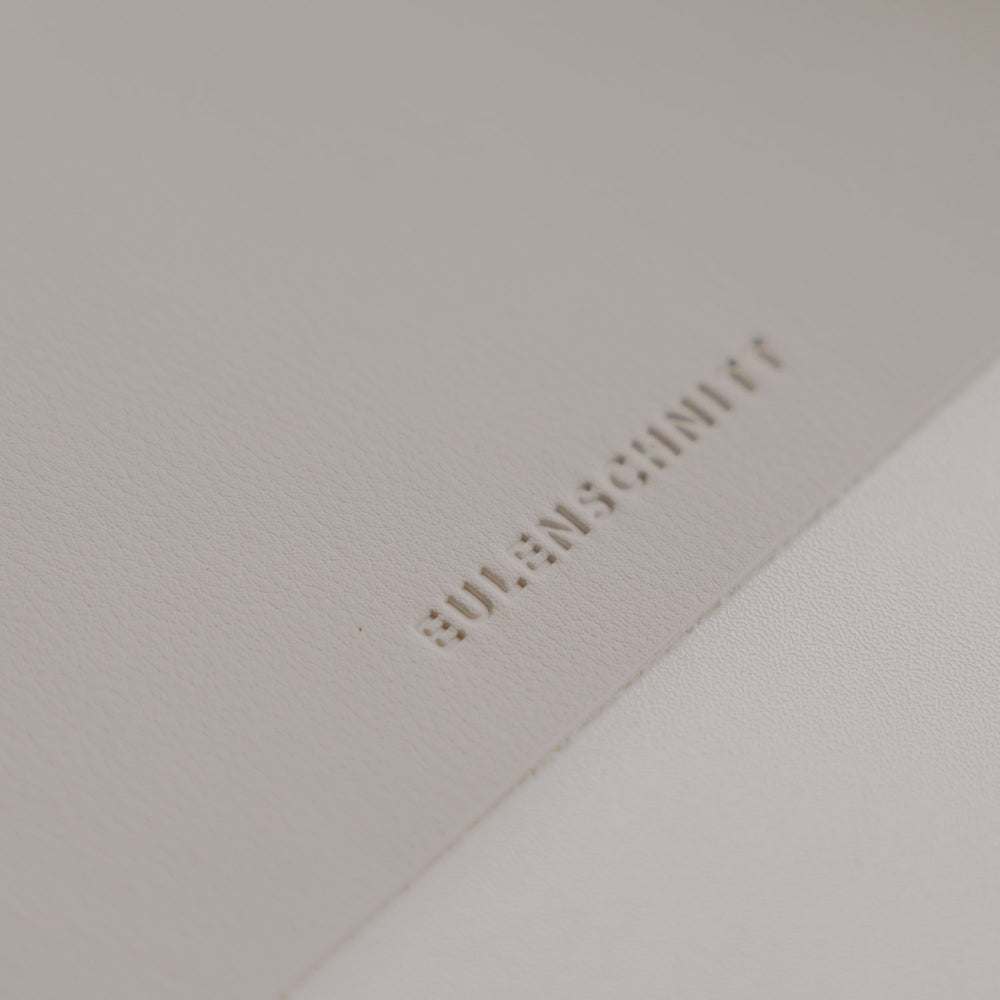 Detail Eulenschnitt Logo auf creme Schreibtischunterlage, hochwertige Lederoptik in sanftem Naturton