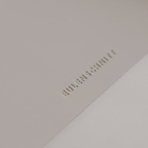 Detail Eulenschnitt Logo auf creme Schreibtischunterlage, hochwertige Lederoptik in sanftem Naturton