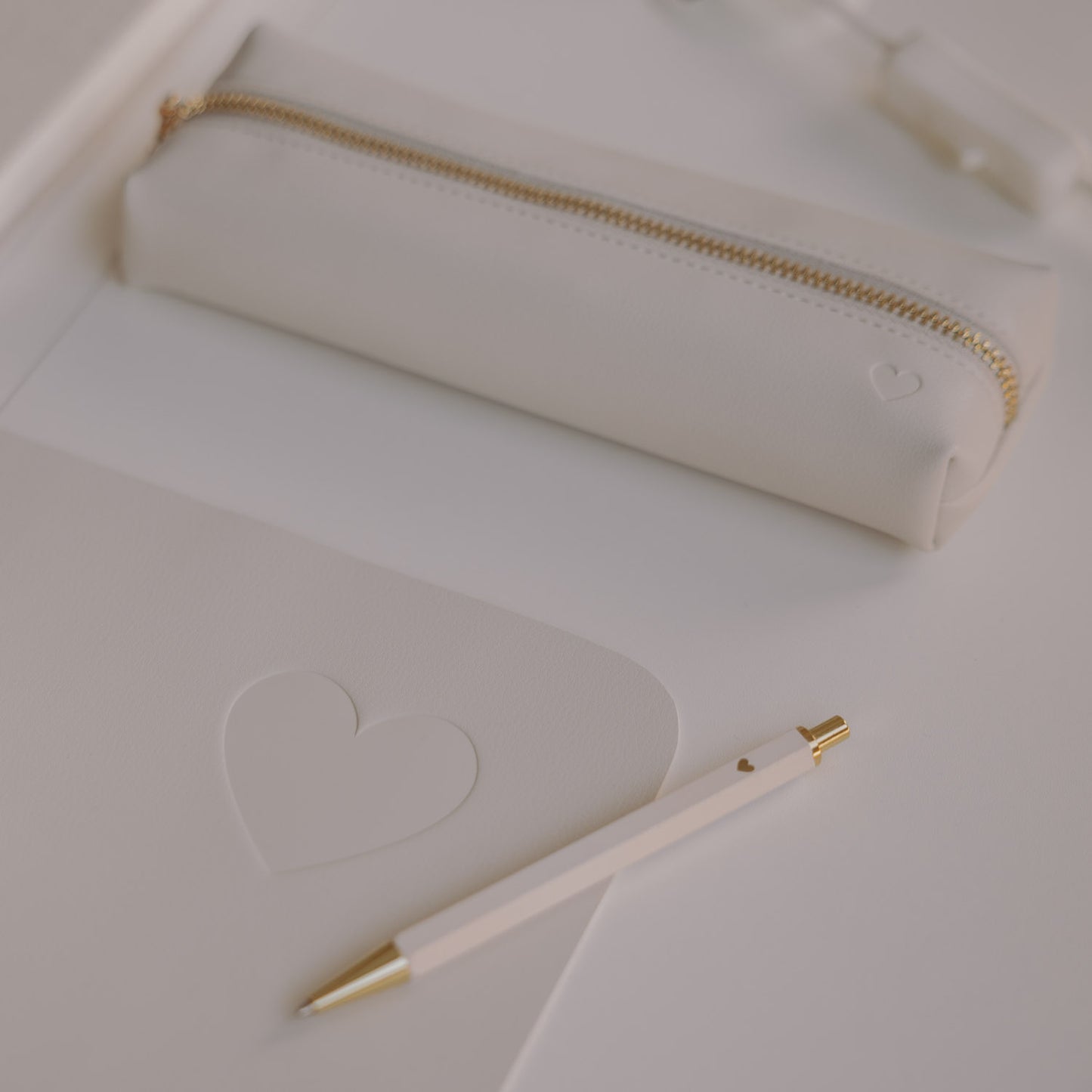 Detail creme Schreibtischunterlage mit Herz-Prägung, Stift und Federmäppchen in hellem Design