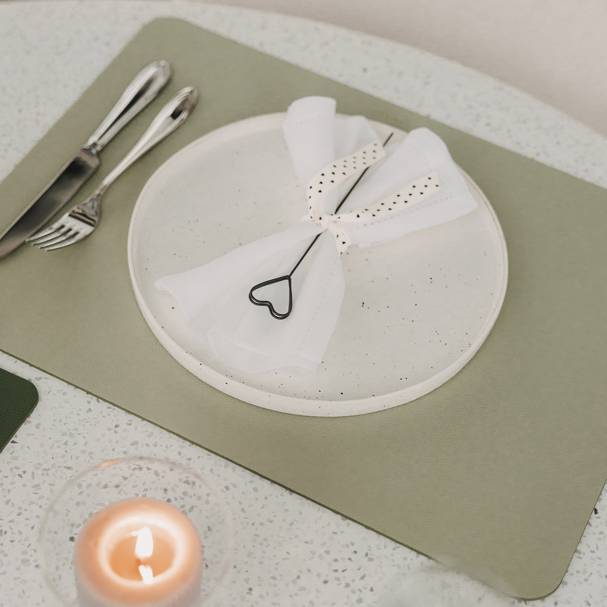 Hellgrünes Platzset mit Teller, Serviette und herzförmigem Serviettenhalter