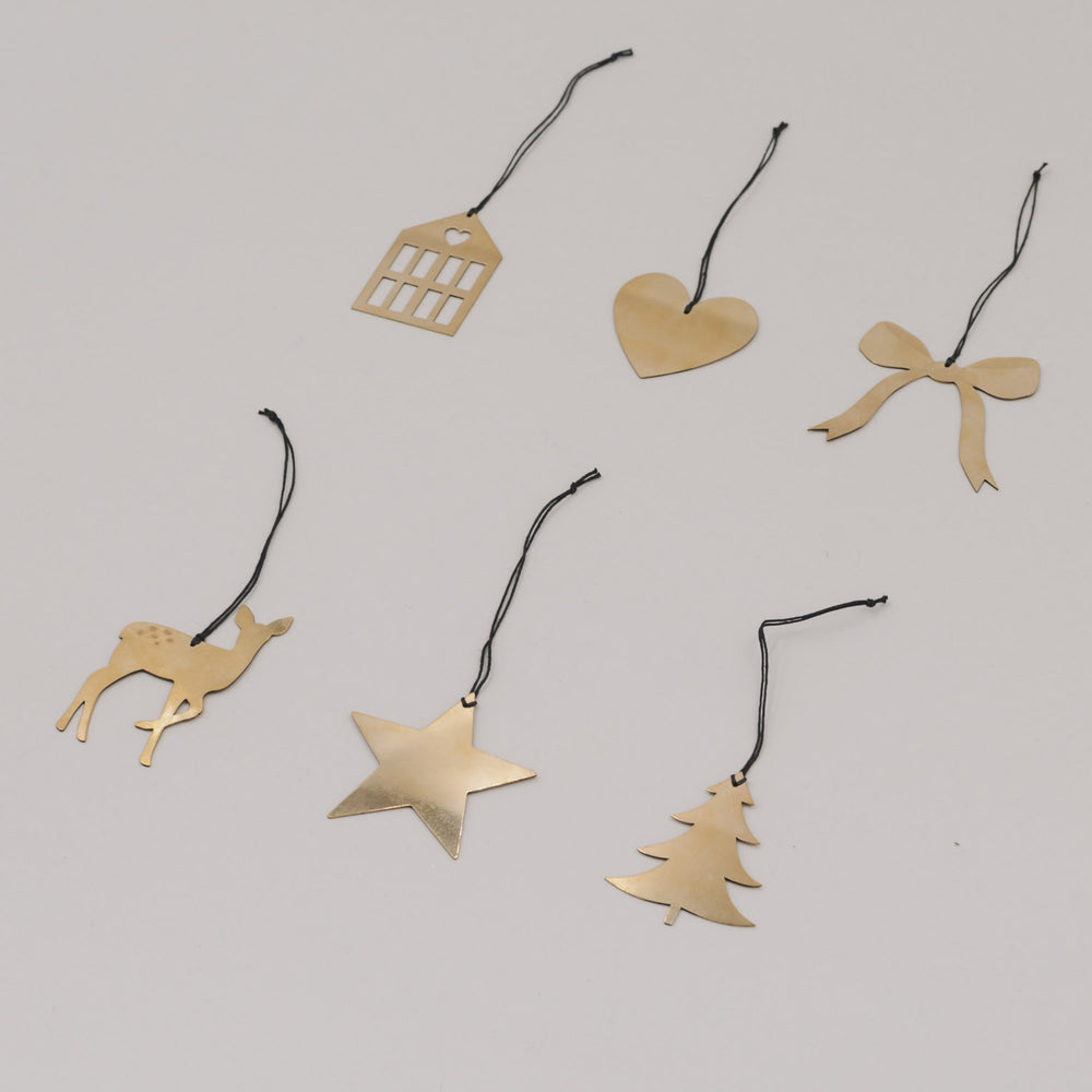 Goldene Anhänger Herz, Stern, Haus, Schleife, Reh und Tanne locker arrangiert auf weißem Untergrund.