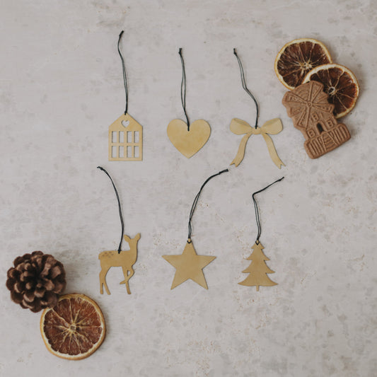 Goldene Weihnachtsanhänger mit Trockenfrüchten und Spekulatius liebevoll auf rustikalem Untergrund dekoriert.