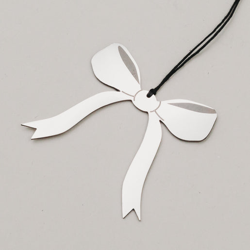 Nahaufnahme des Schleifenanhängers in Silber mit schwarzem Band, auf hellem Hintergrund fotografiert.