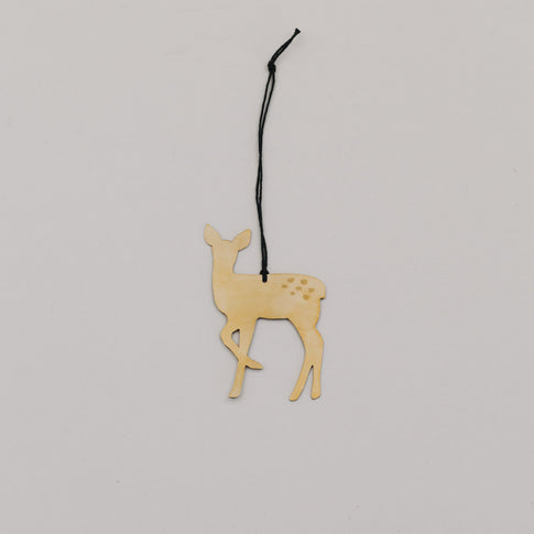 Goldener Rehnhänger aus Metall mit schwarzer Kordel auf hellem Hintergrund, minimalistisch arrangiert.