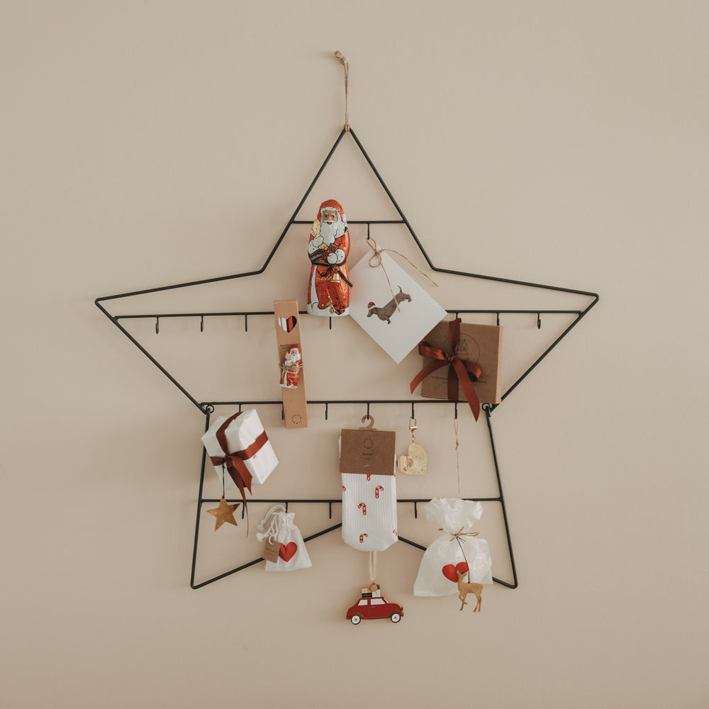 Adventskalender Stern groß aus Metall, dekoriert mit Geschenken, Karten und Anhängern an der Wand