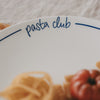 Detailaufnahme des Schriftzugs „pasta club“ auf einem weißen Teller mit dunkelblauem Rand.