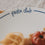 Detailaufnahme des Schriftzugs „pasta club“ auf einem weißen Teller mit dunkelblauem Rand.