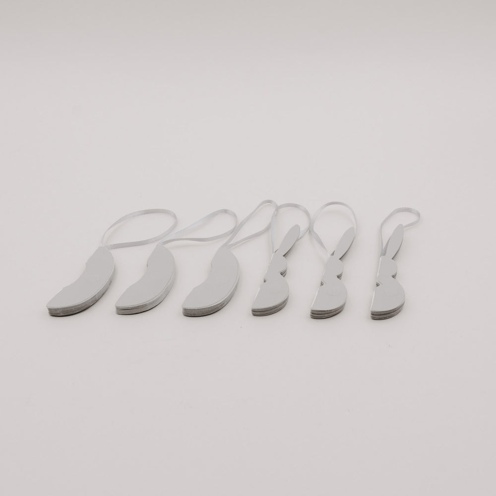 Sechsteiliges Set grauer Papieranhänger in Ei- und Hasenform, flach zusammengelegt.